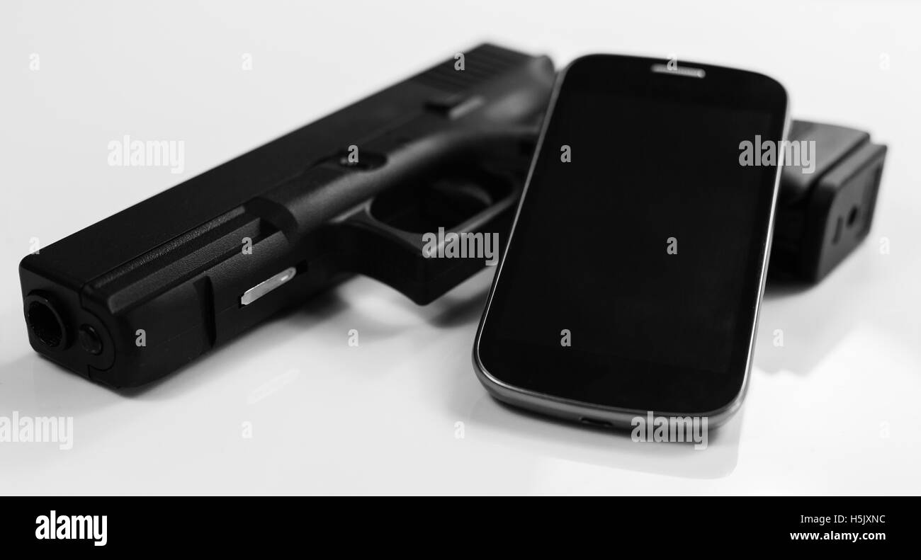 A gun and a modern smart phone, black and white Stock Photo