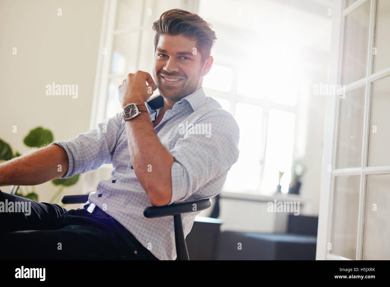 Portrait of handsome young man sitting at home and smiling. Caucasian man looking happy. Stock Photo