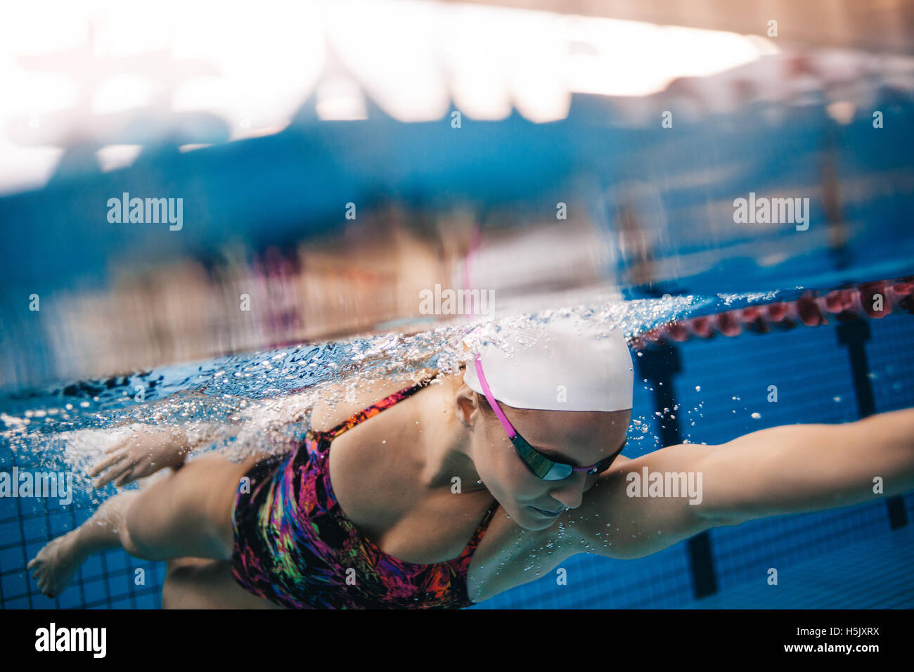 Underwater shot of woman swimming in pool. Young female swimming the front crawl in a pool. Stock Photo