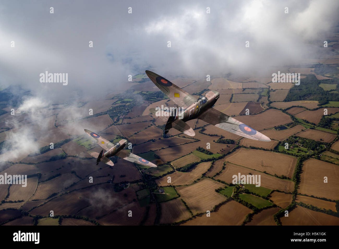 A depiction of Supermarine Spitfire Mk I fighters from 65 Squadron, in Battle of Britain camouflage, over English countryside. Stock Photo