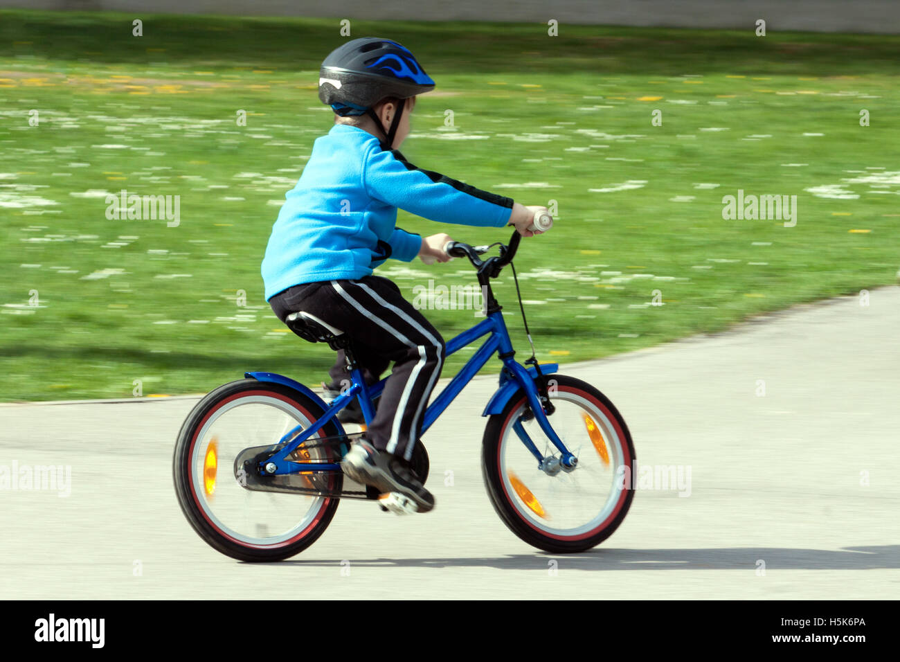 child on a bicycle at asphalt road on traffic playground - blurred panning method Stock Photo