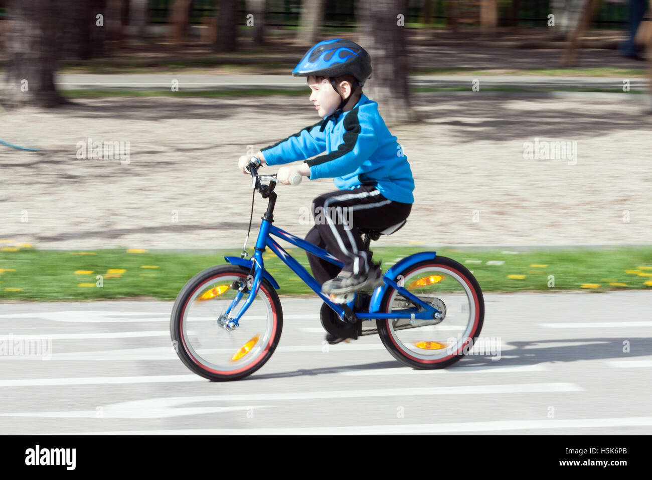 child on a bicycle at asphalt road on traffic playground - blurred panning method Stock Photo