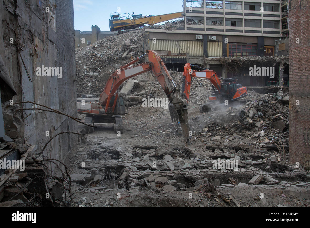 Heavy plant machinery wrecking and breaking up buildings on an inner city demolition site that looks like a war zone. Stock Photo
