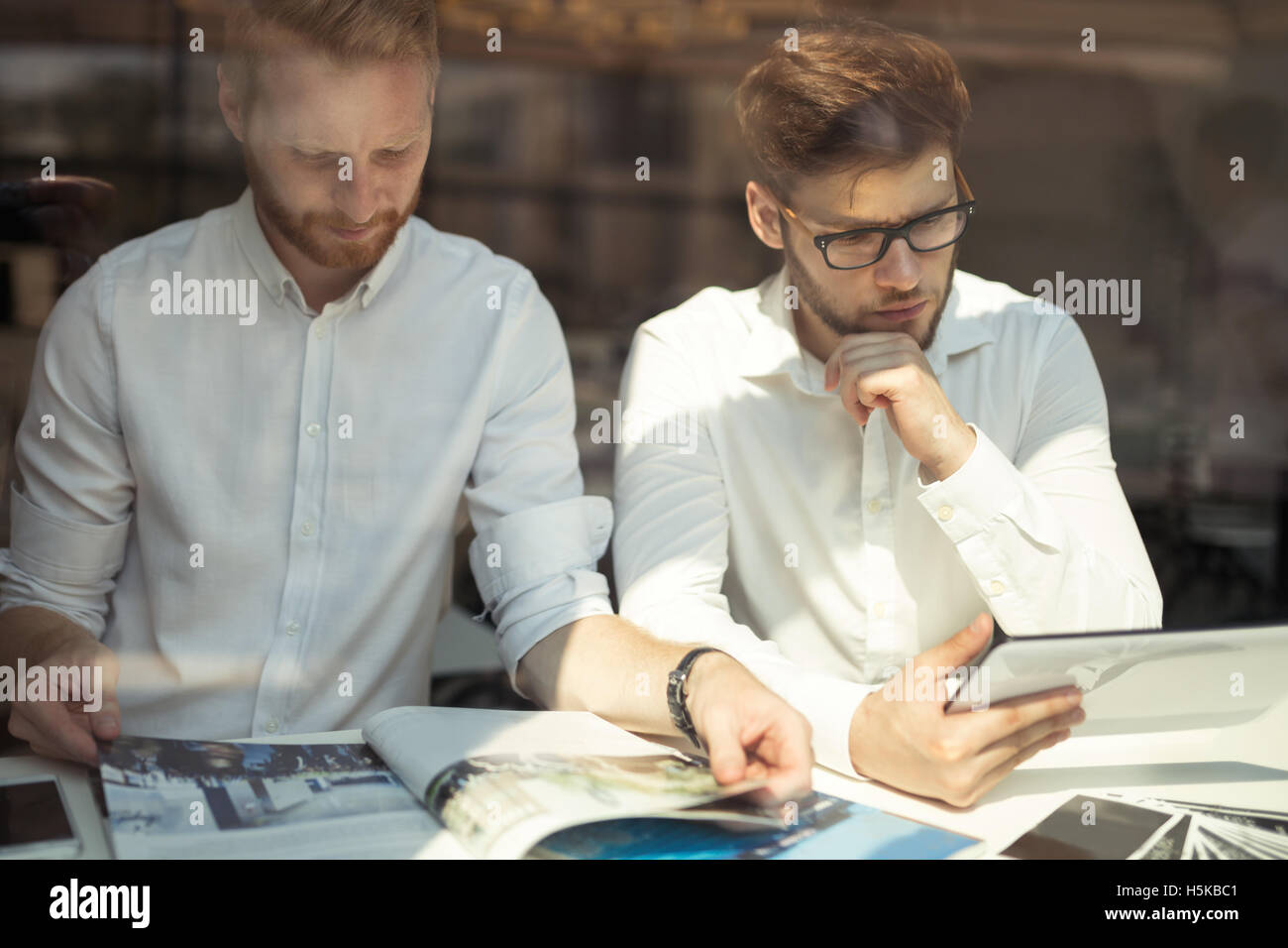 Colleagues reading newspaper together while on break Stock Photo