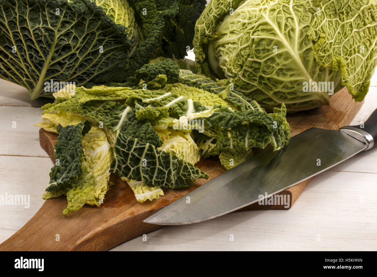 organic savoy cabbage is cut on a wooden board in small strips and prepared for cooking Stock Photo