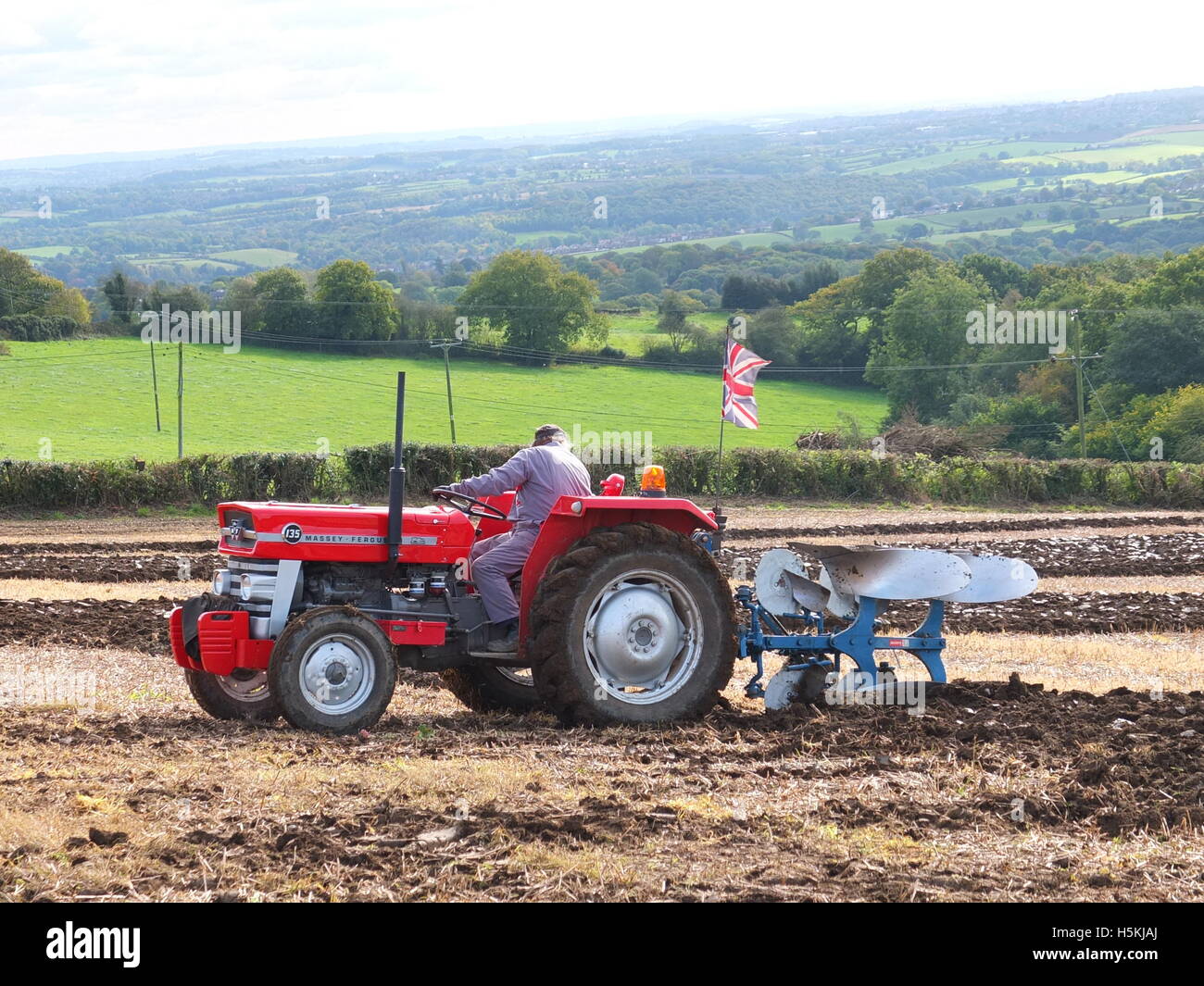 A farmer flying the Union Jack flag from his tractor competing in the Ashover Ploughing Match held at Highoredish Farm, Derbys. Stock Photo