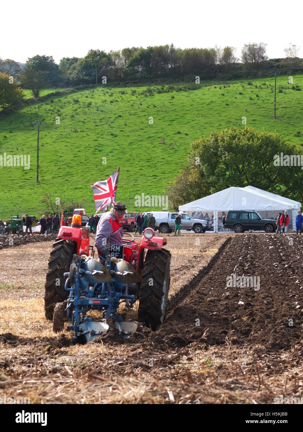 A farmer flying the Union Jack flag from his tractor competing in the Ashover Ploughing Match held at Highoredish Farm, Derbys. Stock Photo