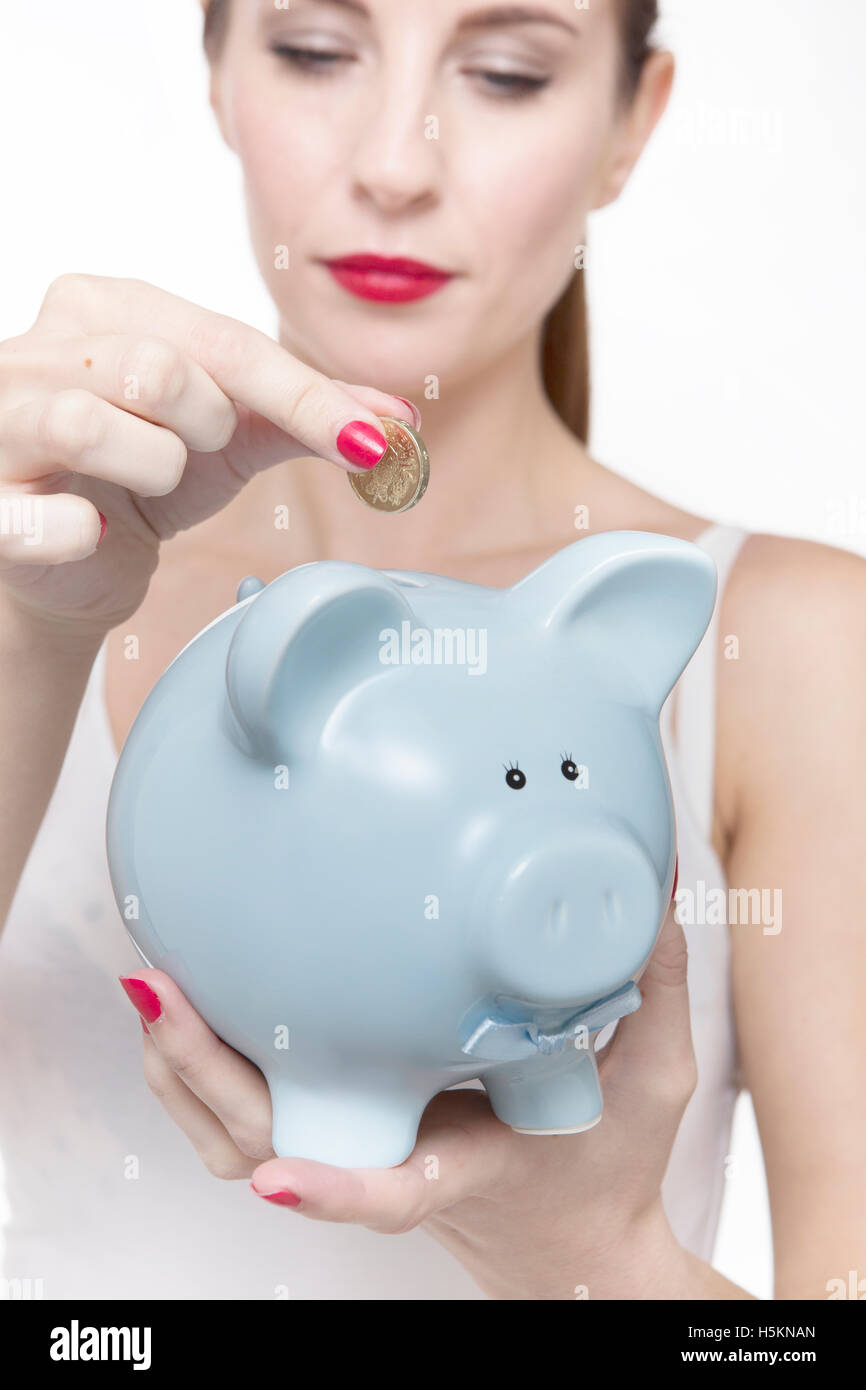 Young woman putting money in her piggy bank Stock Photo - Alamy