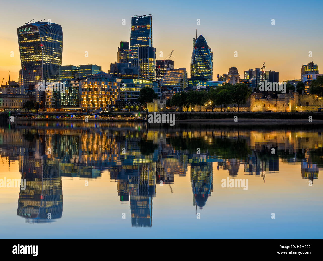 Illuminated London cityscape at sunset with reflection from river Thames Stock Photo