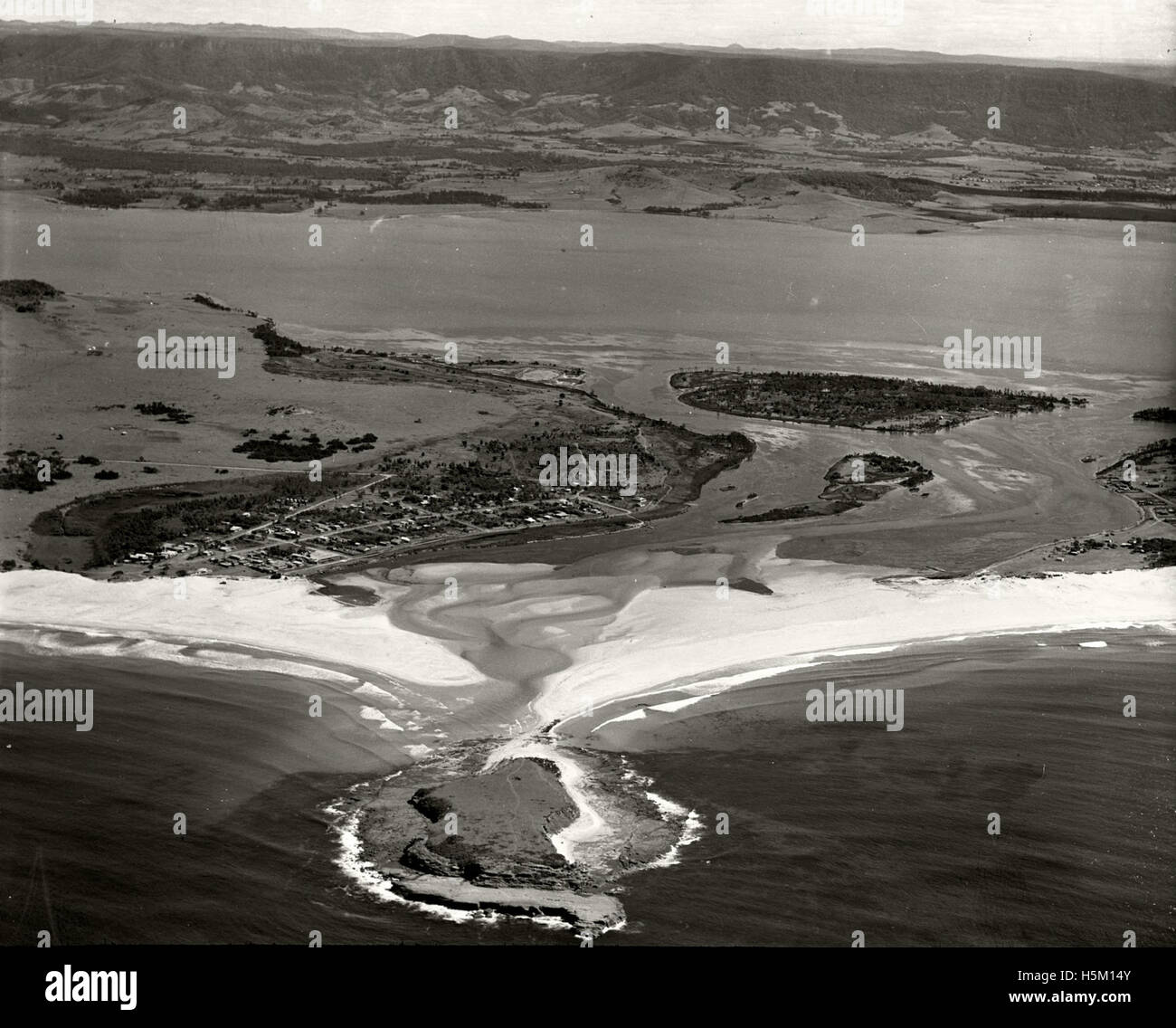 A monochrome aerial photograph taken in 1936 showing Lake Illawarra and Shellharbour in New South Wales, Australia, as part of the Adastra Aerial Survey. The image documents the landscape and development of the area during the 1930s. Stock Photo