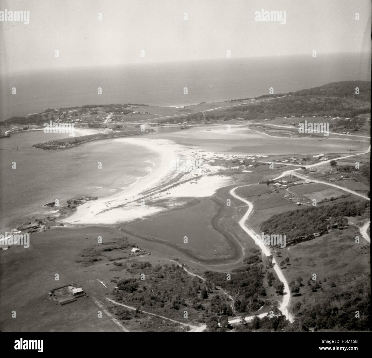 An aerial view of Bermagui looking east in November 1937, showcasing the landscape and surrounding natural features. The image is part of the Adastra Aerial Survey Collection, reflecting mid-20th century photography techniques. Stock Photo