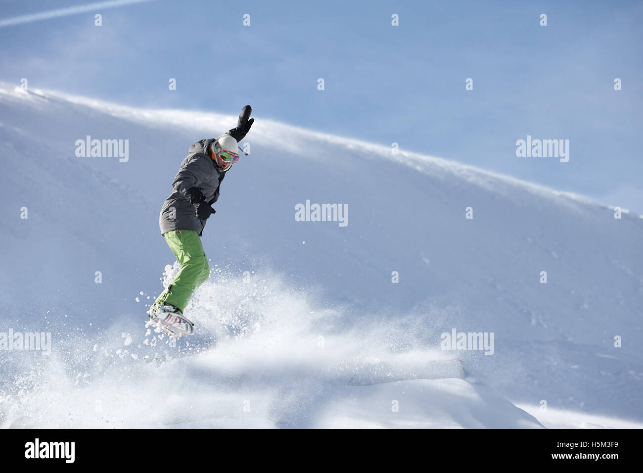 Snowboarder jumping against snow slope background Stock Photo