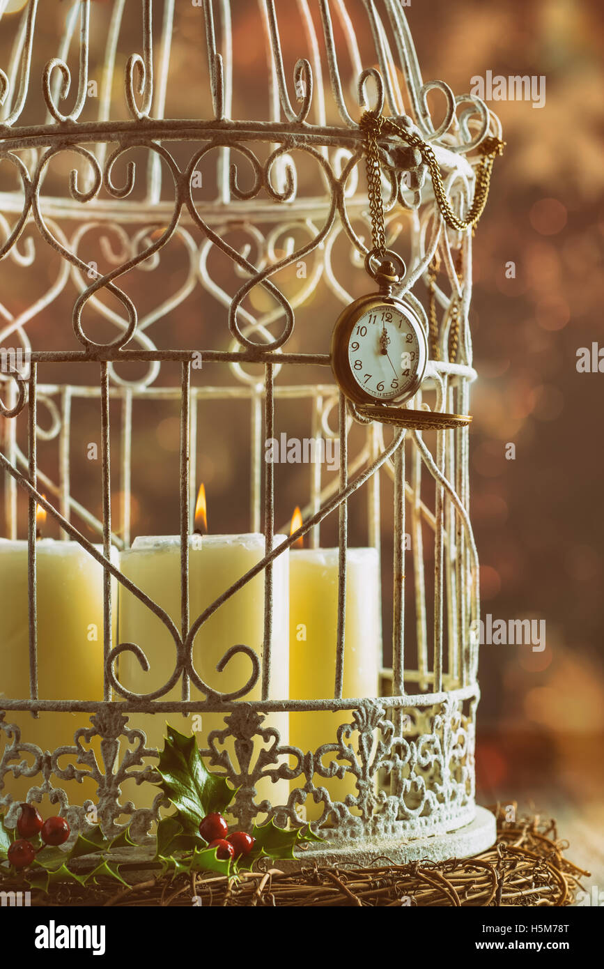 Pocket watch showing midnight on birdcage filled with candles Stock Photo