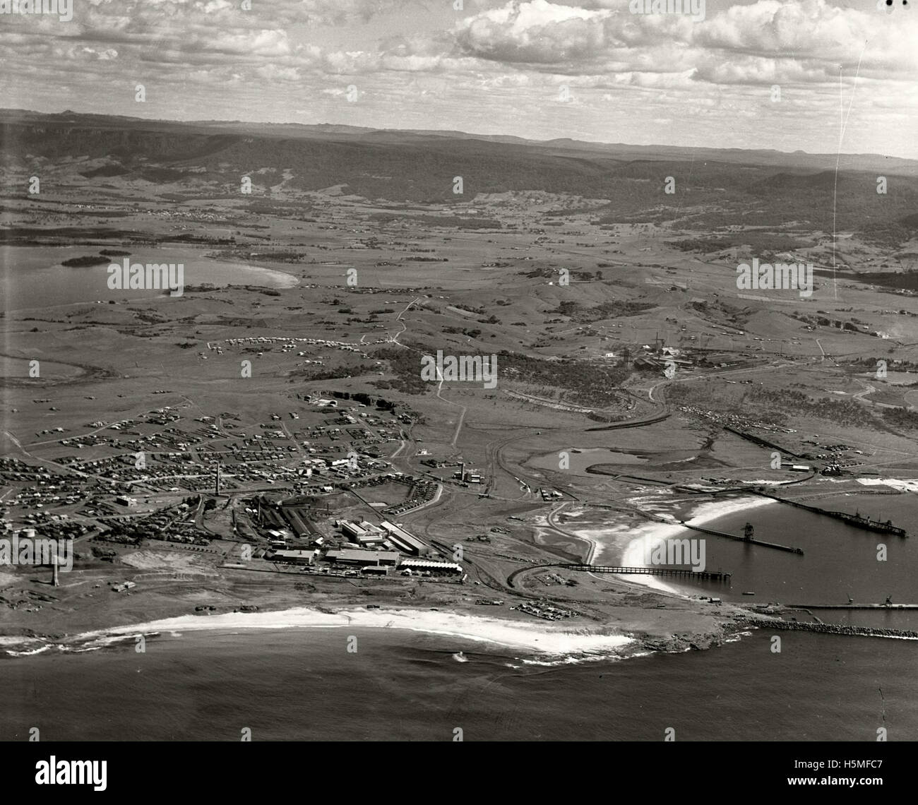 This aerial photograph shows Port Kembla in 1936, looking west. It is part of the RAHS Adastra Aerial Survey Collection, providing historical insight into the development of the port and surrounding areas in the Illawarra region of Australia. Stock Photo