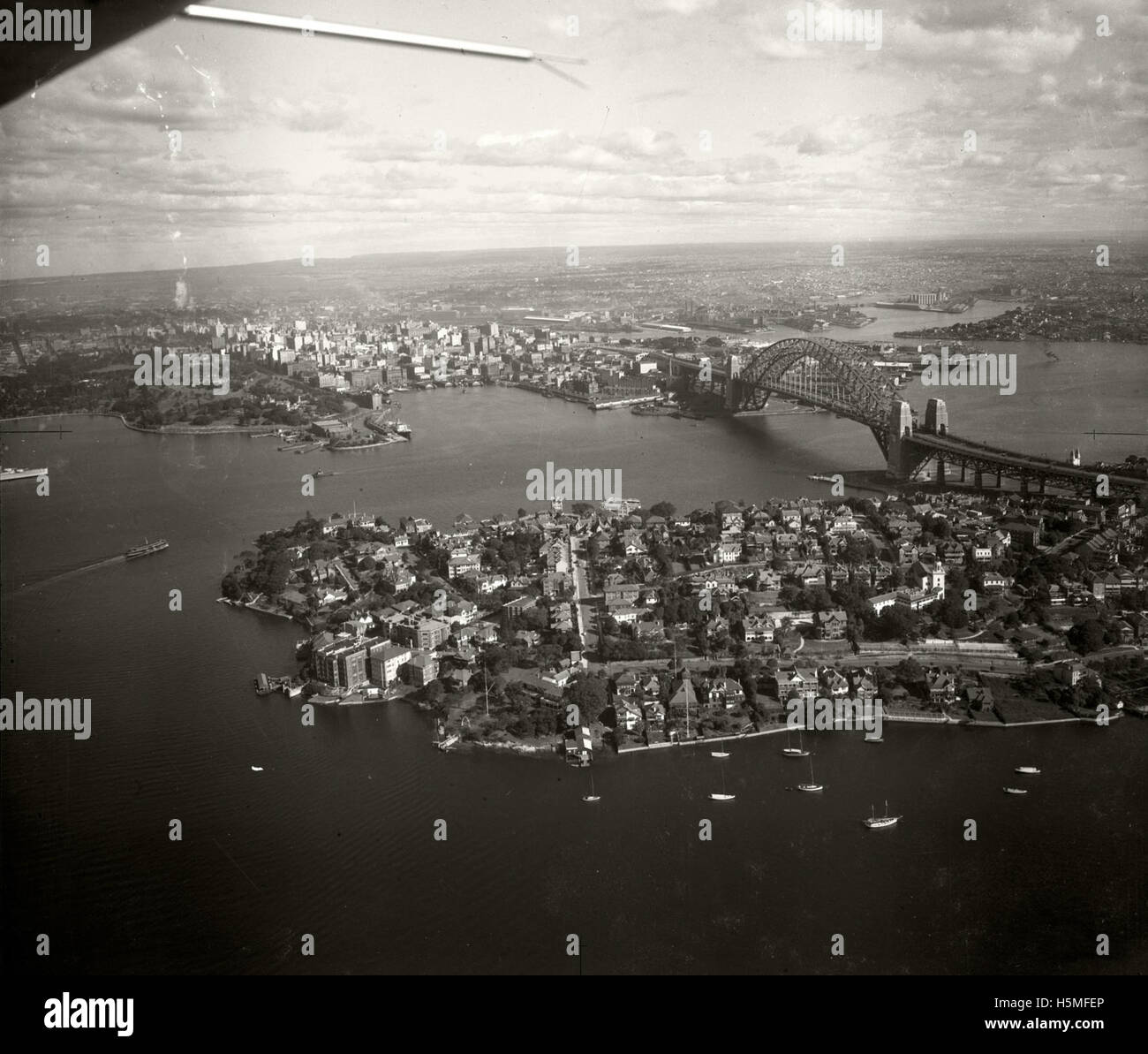 This 1937 aerial photograph captures Kirribilli Point and the surrounding area of Sydney, offering a clear view of the harbor, residential areas, and landmarks. It is part of the Adastra Aerial Survey Collection, showcasing Sydney's development during the mid-20th century. Stock Photo
