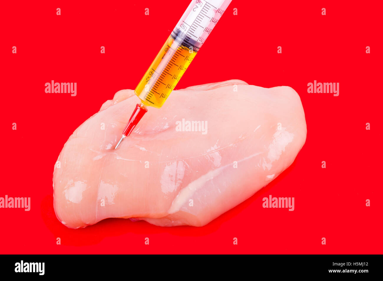 Syringe with liquid being injected to a piece of meat. Conceptual illustration for Hormones and antibiotics in food production. Stock Photo