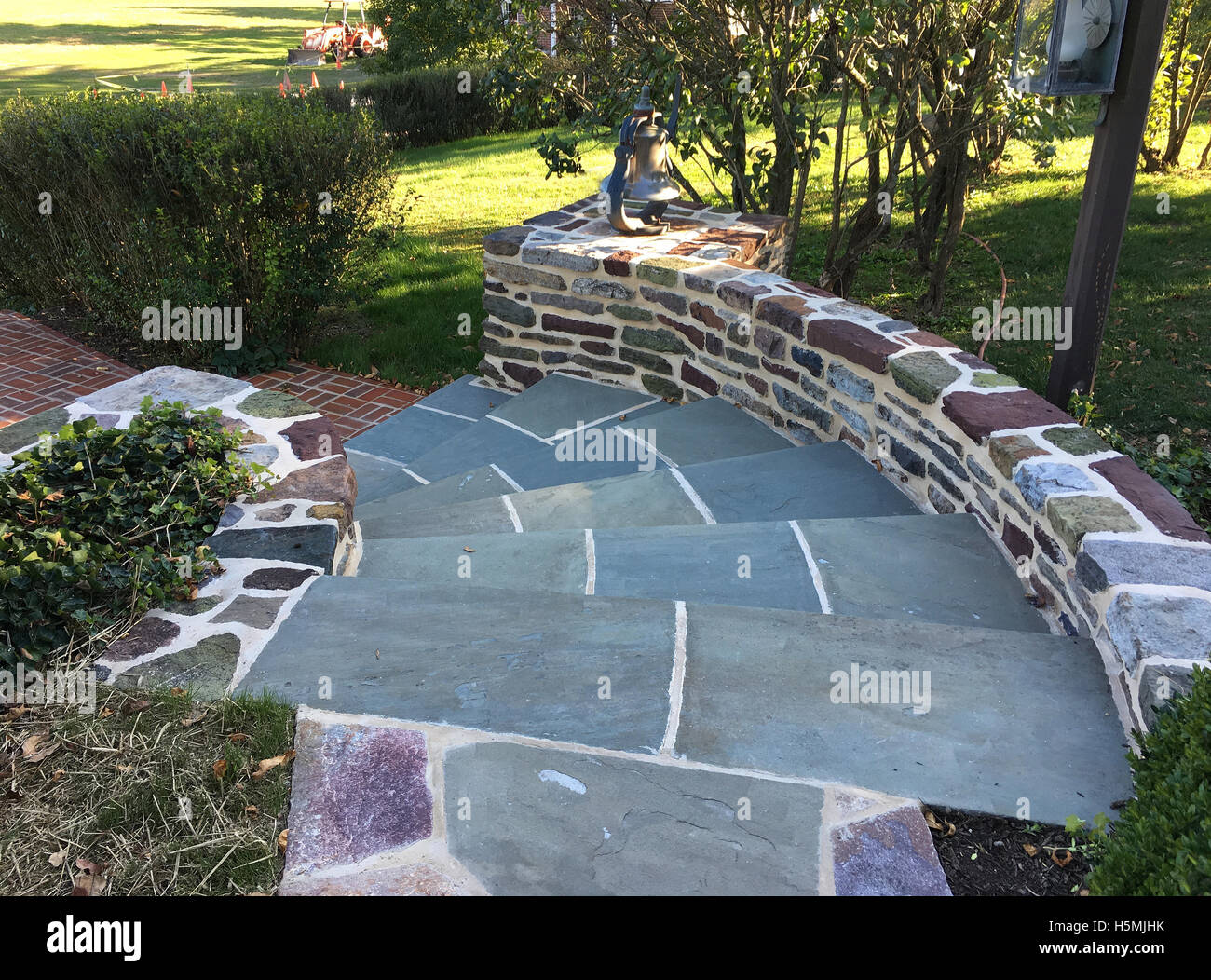 flagstone pavers for curved steps leading down to a brick pathway in a garden Stock Photo