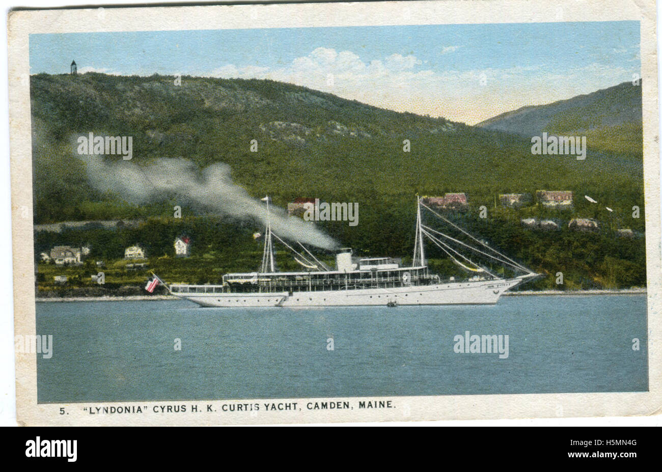 A colorized view of the steam yacht &quot;Lyndonia.&quot;  Mount Battie with a tower can be seen in the background.  Houses are also visible--this stretch is likely Sherman's Cove.  The Lyndonia belonged to Cyrus H.K. Curtis and was built in 1920 by the Consolidated Ship Company of Morris Heights, New York.  In 1940, she was sold to Pan American Airways.  Her name was changed to M.V. Southern Seas.  The U.S. Army purchased her in 1941 for use as a quarters ship, and she was officially rechristened the U.S.S. Southern Seas in 1942.  She sank off of Okinawa during Typhoon Louise in October 1945. Stock Photo