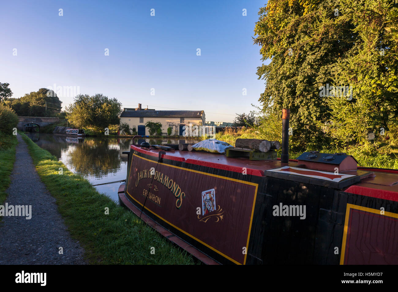Moored narrowboat and a pretty cottage on the banks of the Moss Hall Winding Hole, Shropshire Union Canal, Audlem, Cheshire, UK Stock Photo