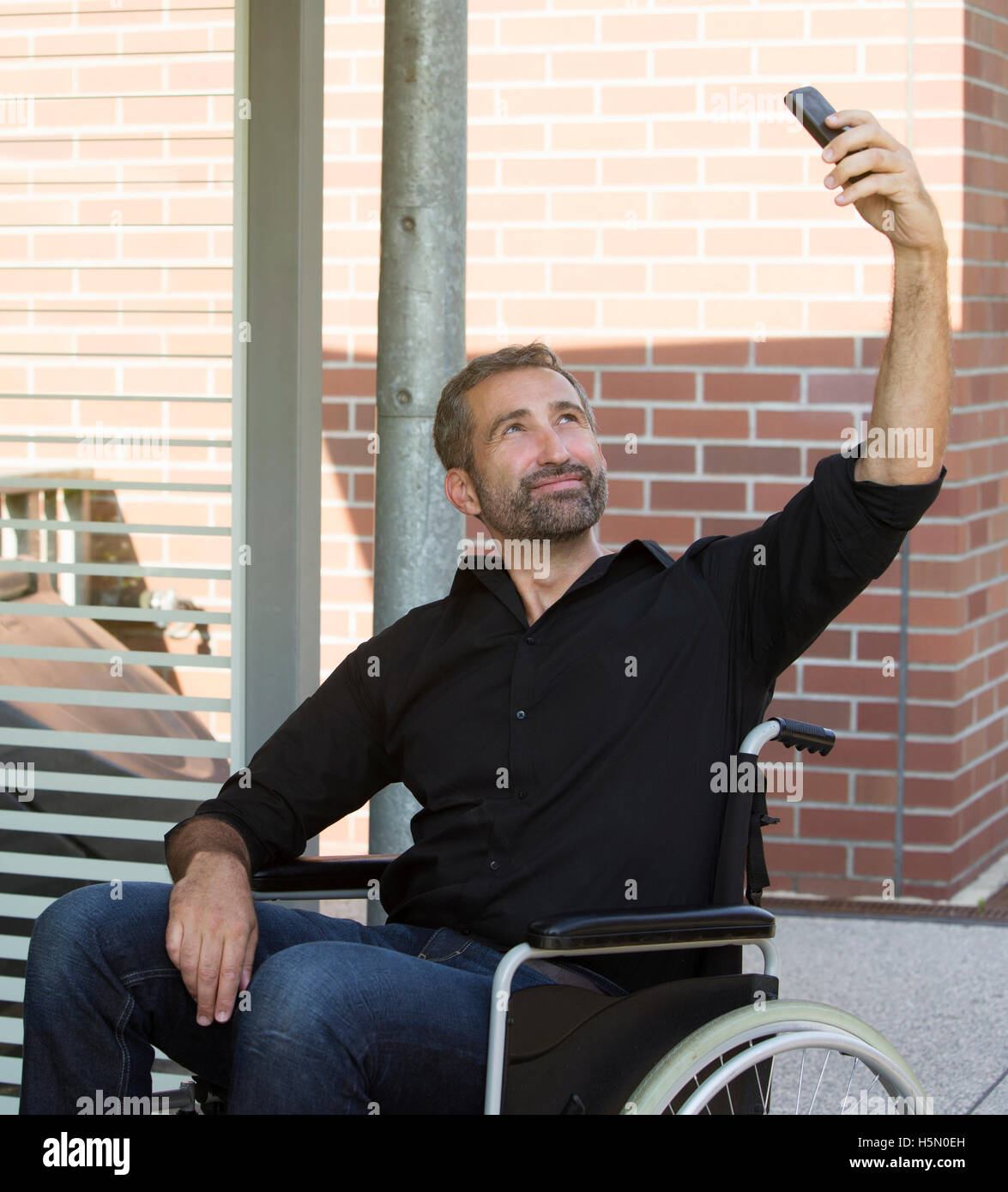 handsome man in wheelchair taking a selfie and smiles Stock Photo - Alamy