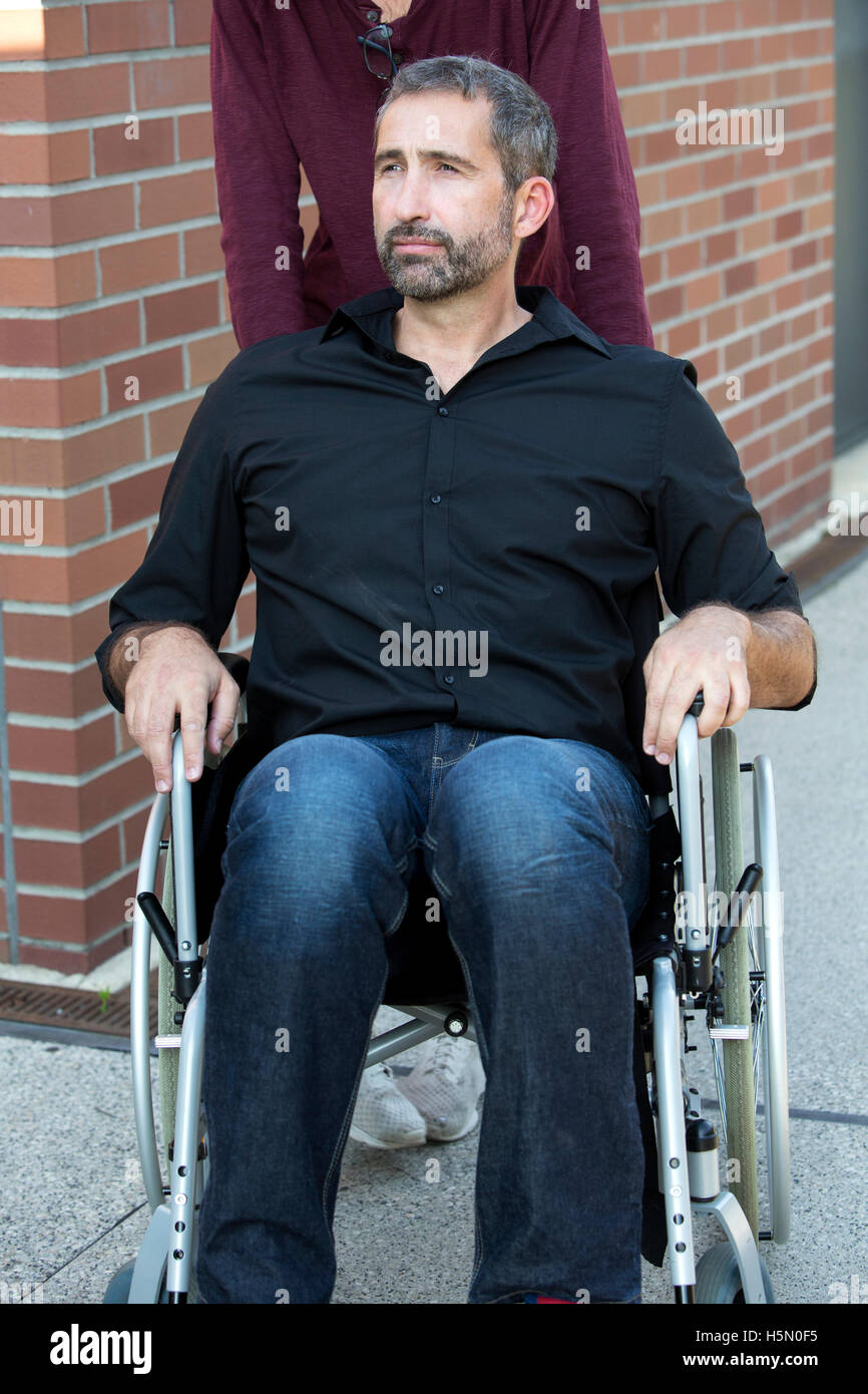 handsome man sitting in wheelchair and looking confident Stock Photo