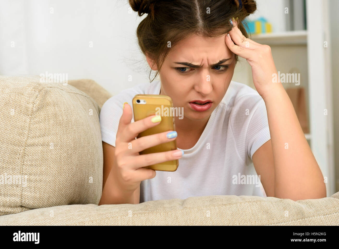Happy girl using her smartphone on the couch at home Stock Photo