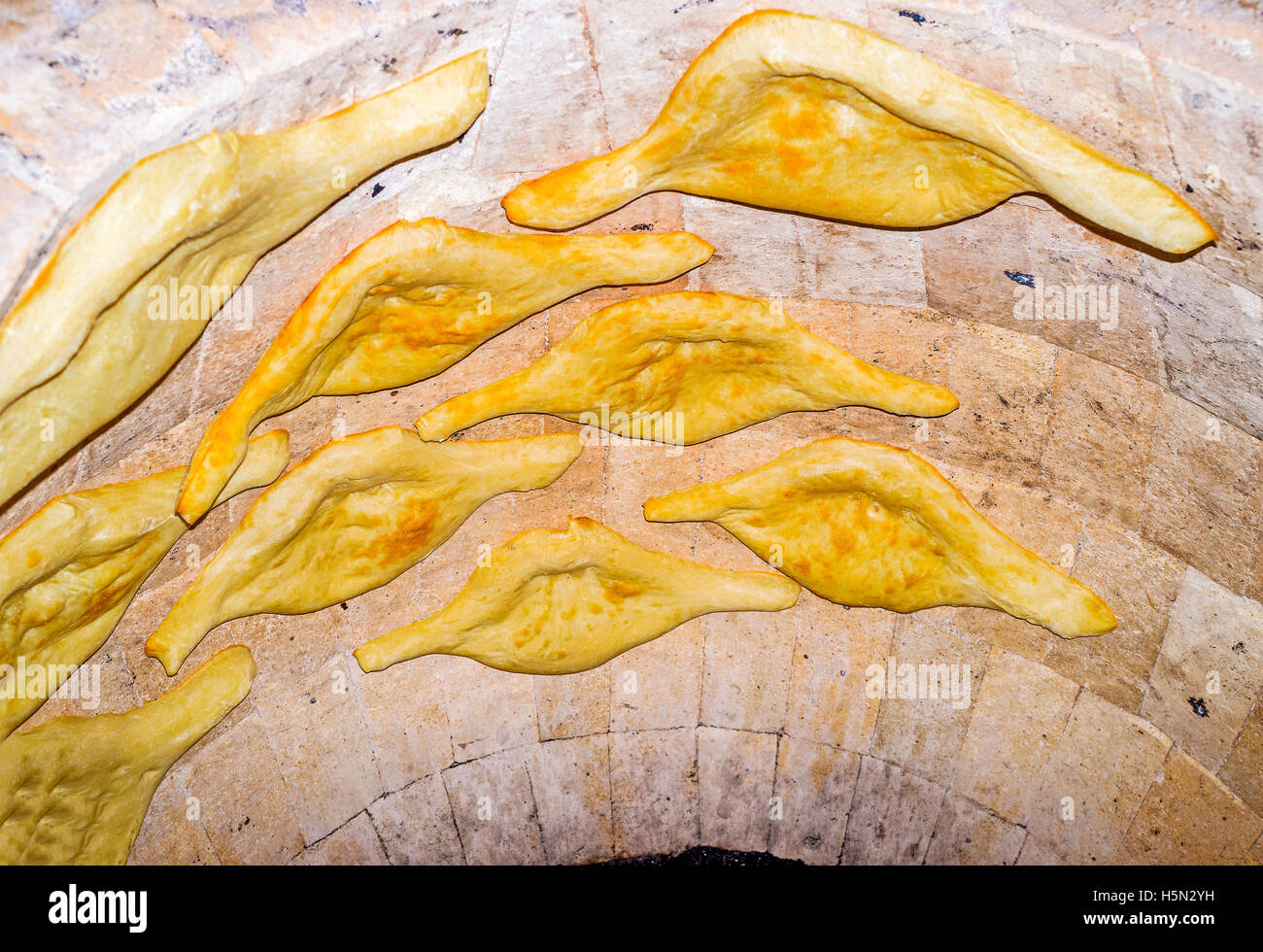The traditional pita bread is cooking in the stone tandoor oven