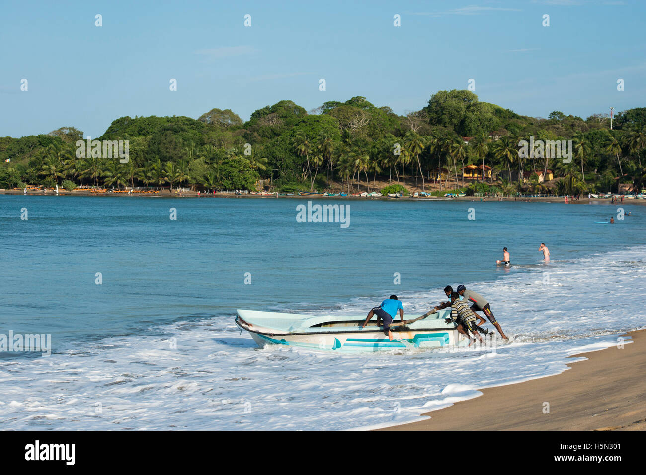 Fishermen pushing a boat into sea, Arugam Bay, Sri Lanka Stock Photo