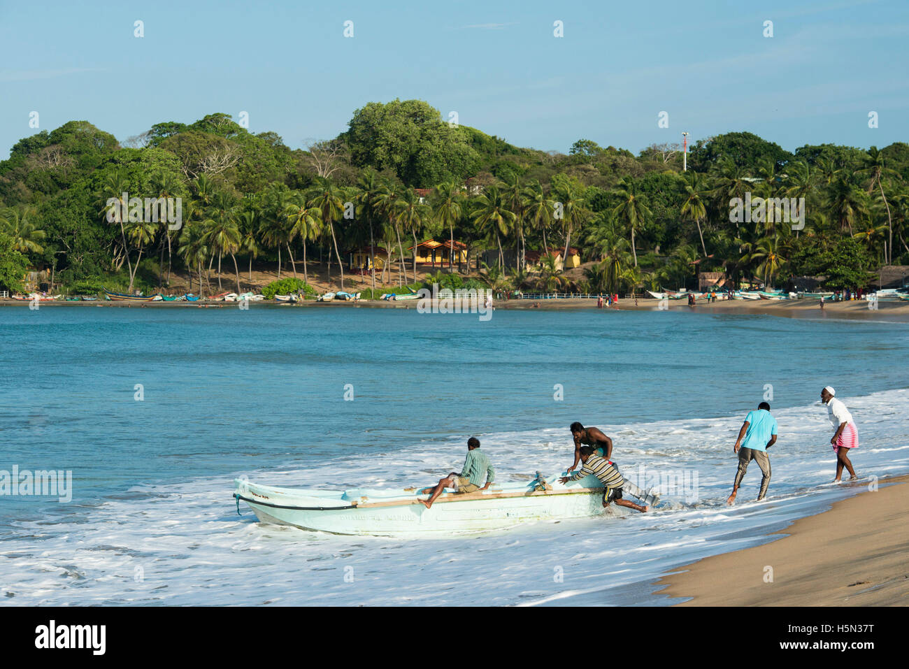 Fishermen pushing a boat into sea, Arugam Bay, Sri Lanka Stock Photo