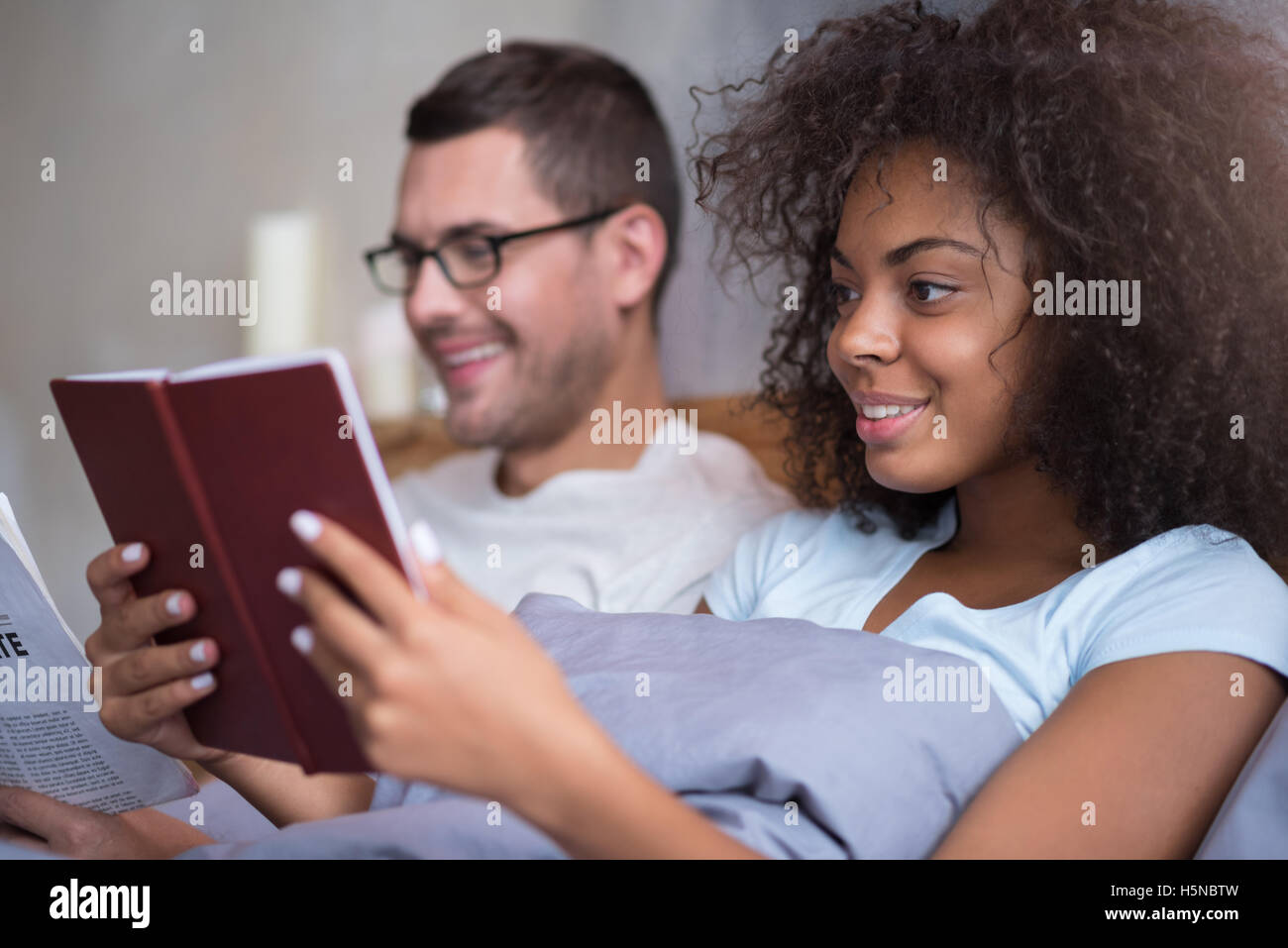Happy couple reading together in bed Stock Photo