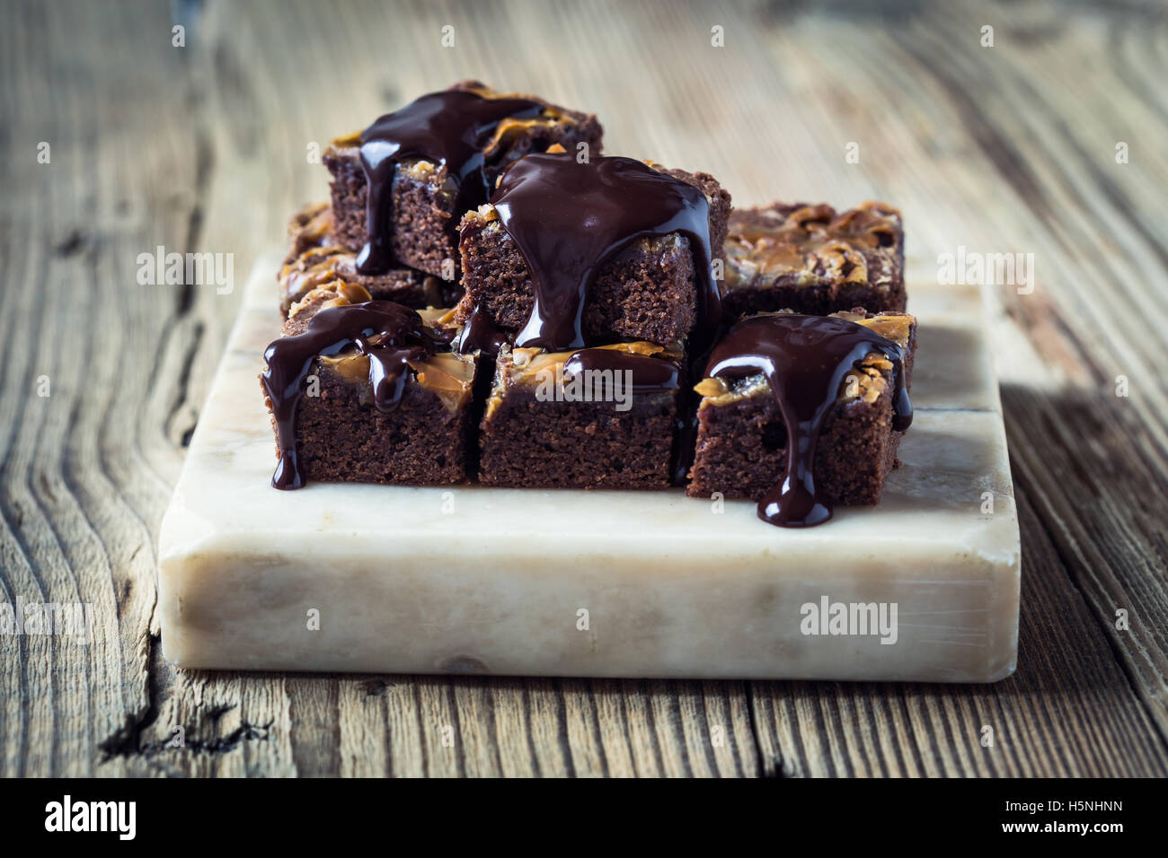Homemade caramel chocolate brownies with dark chocolate ganache served on marble stand Stock