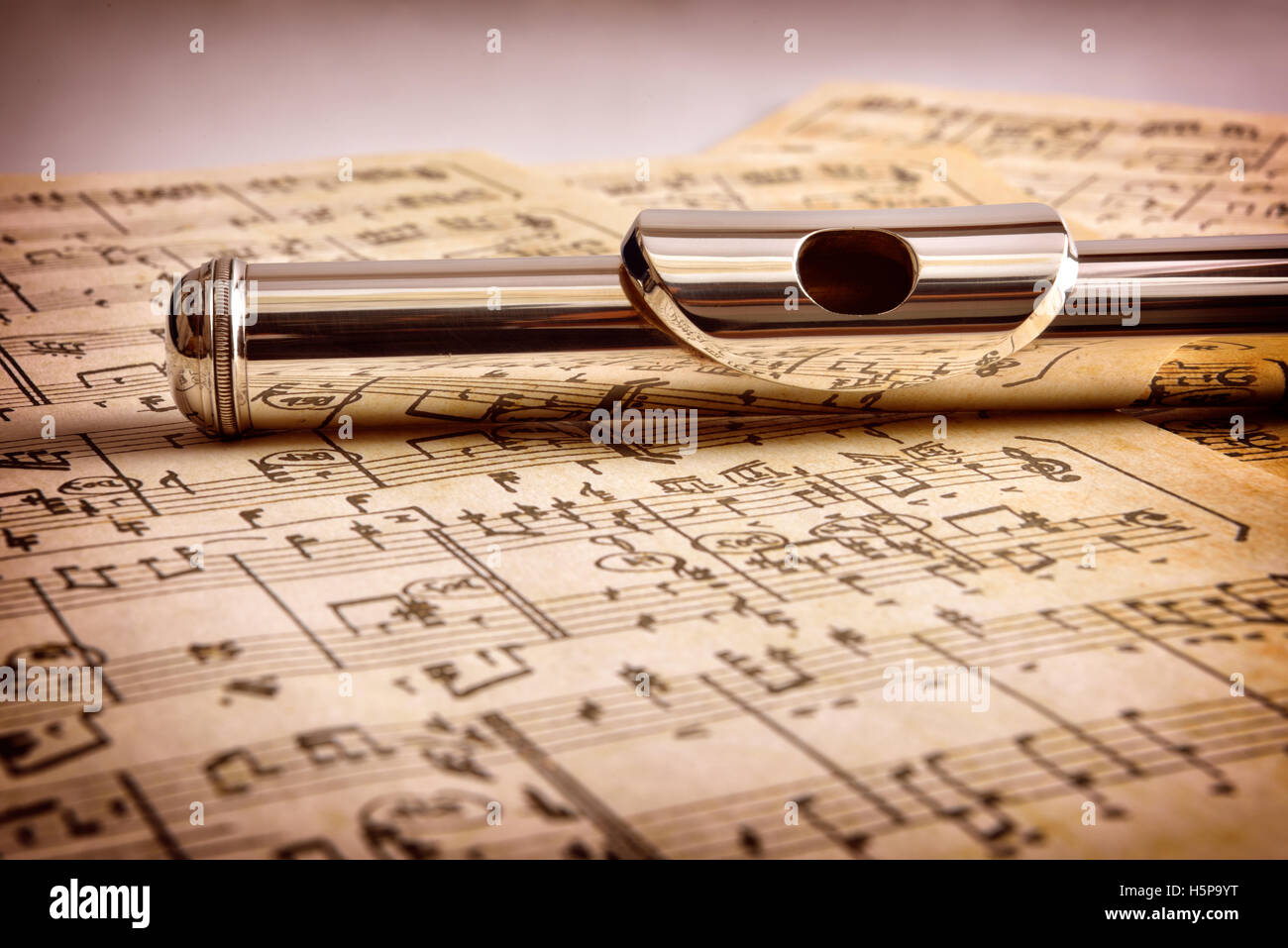 Mouthpiece of flute on old handwritten sheet music close up. Horizontal