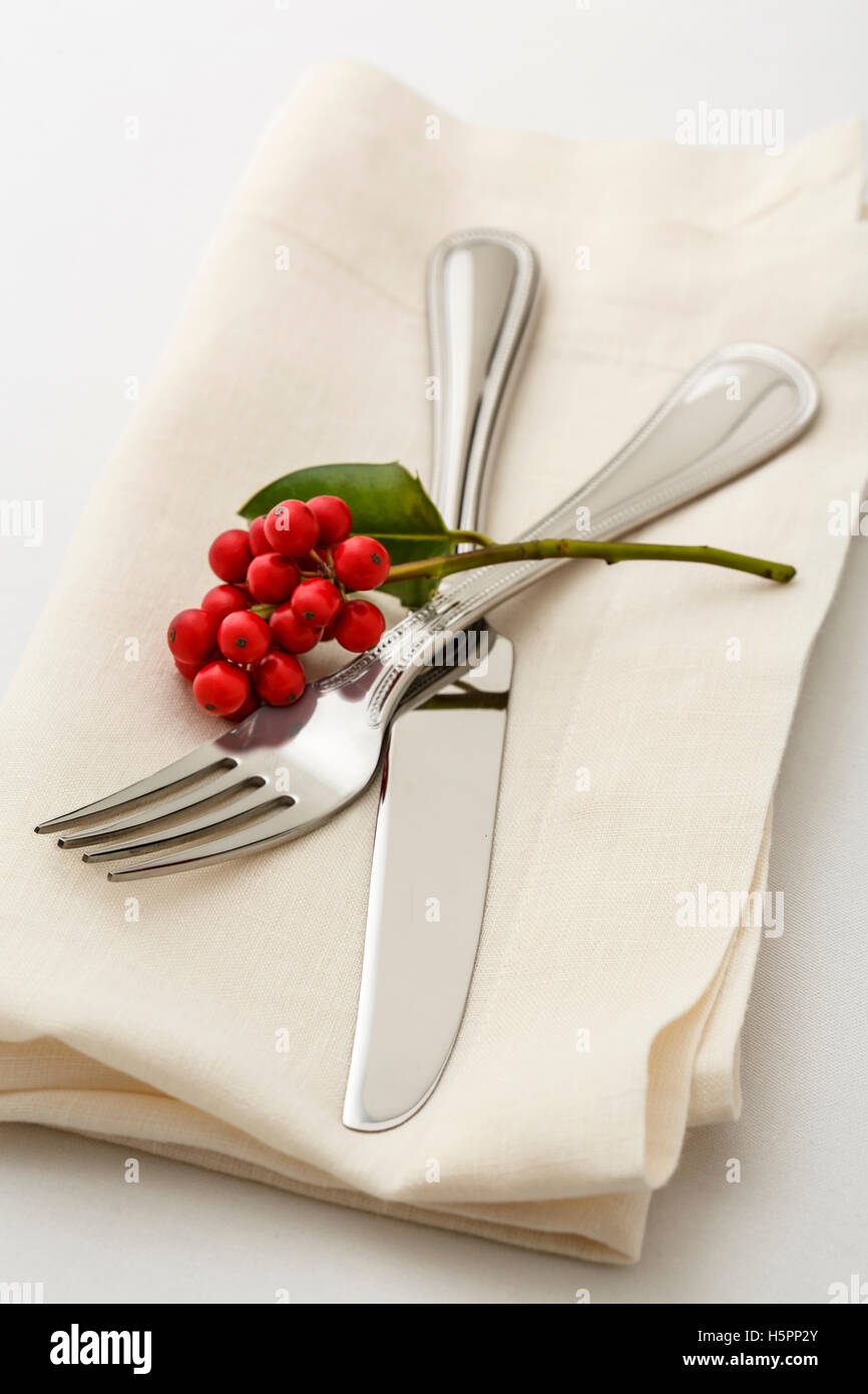 Simple, classic Christmas holiday table setting place setting with high quality silverware fork and knife on white linen napkin Stock Photo