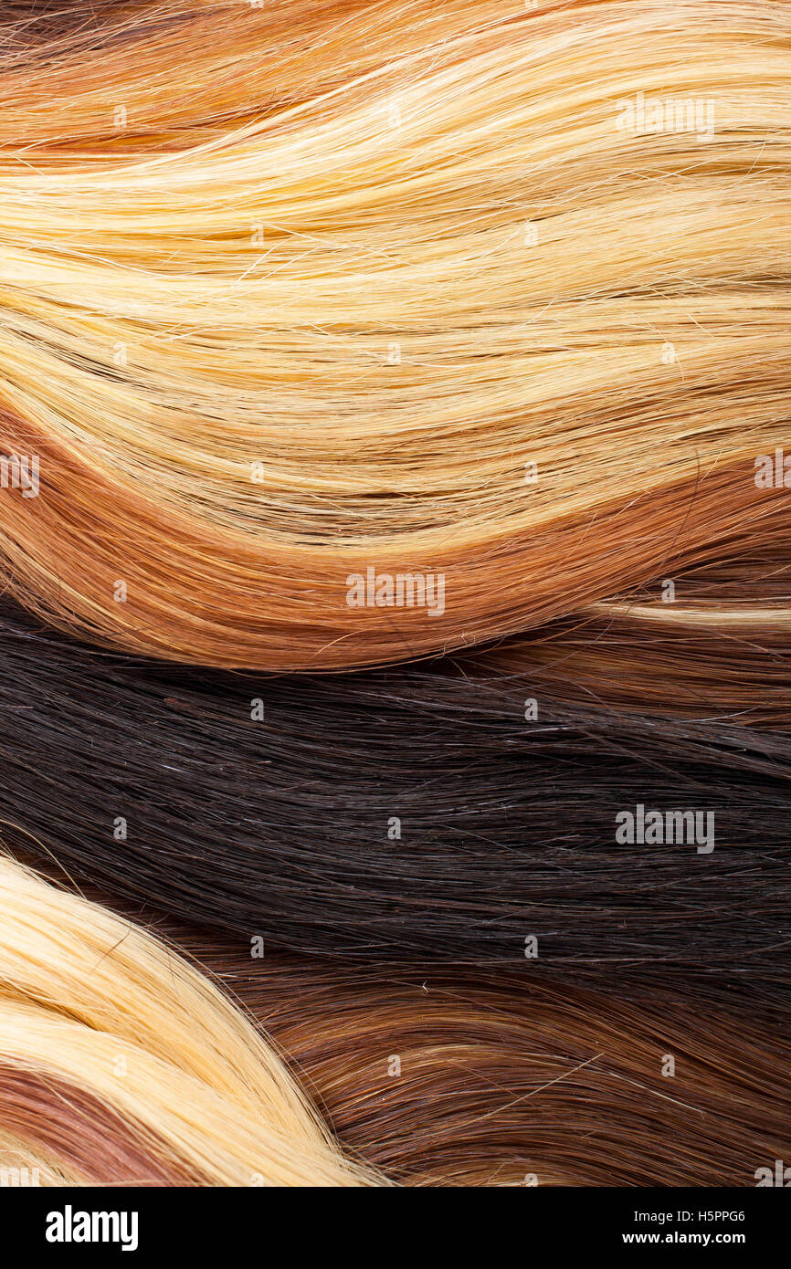 Blond red and black real women human hair extension weft close up photo. Real European healthy long hear. Stock Photo