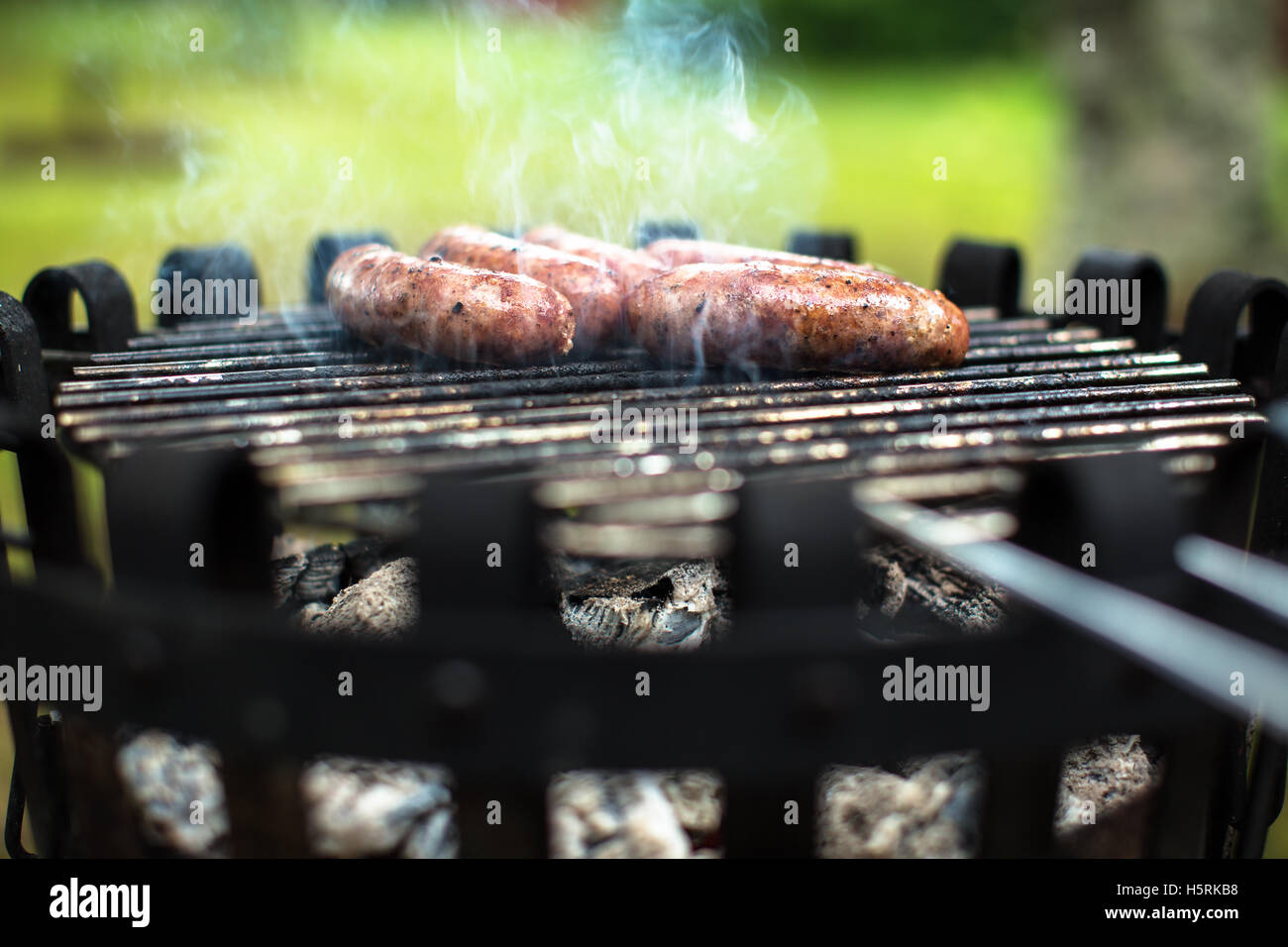 A couple of sausages on the barbecue with hot coal and smoke Stock Photo