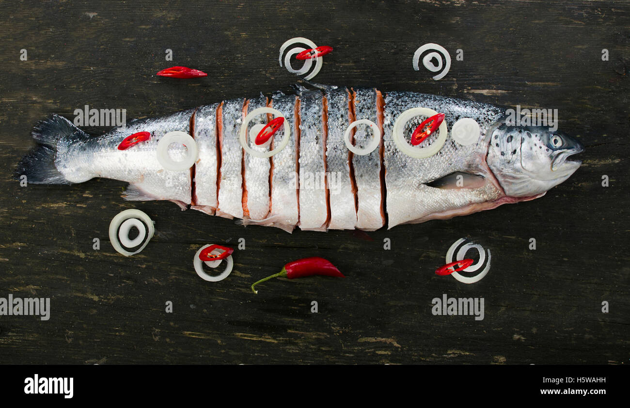 Raw salmon on a dark rustic board. Top view. Fish preparing for cooking. Healthy food or diet nutrition concept. Stock Photo