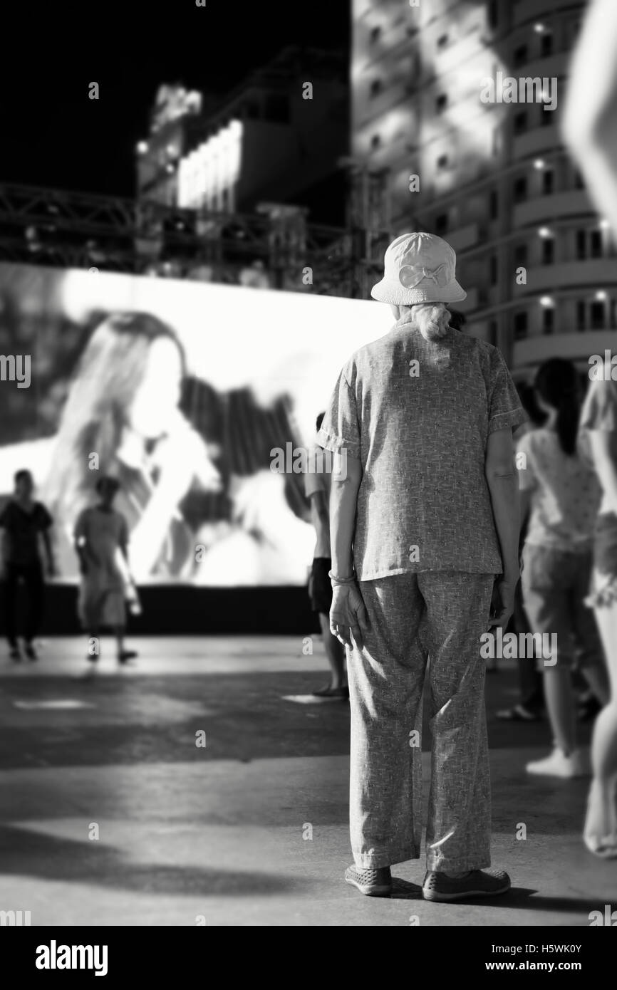 Old woman/lady standing alone in the street Stock Photo