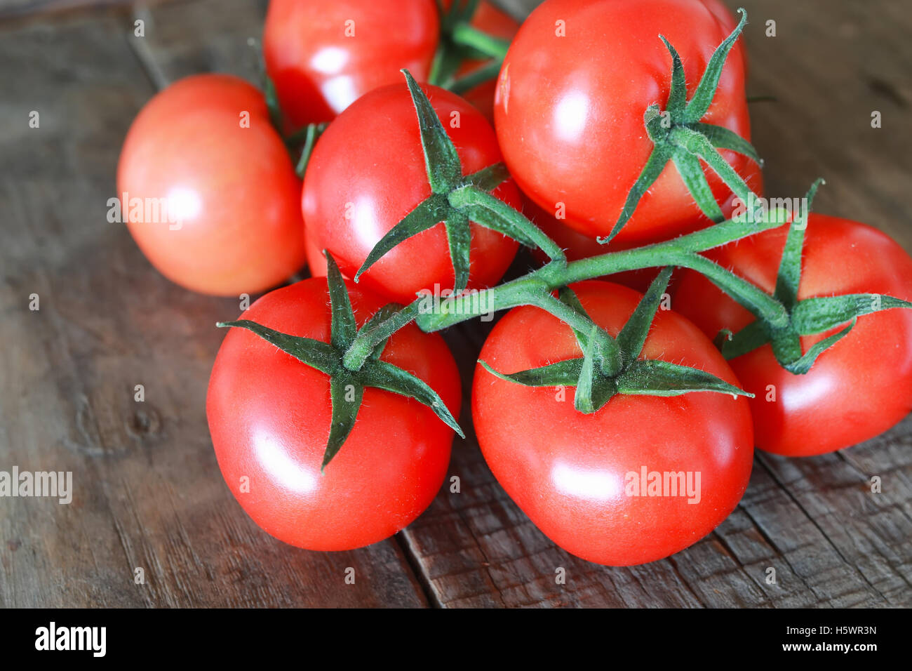 branch of tomatoes on wooden background Stock Photo - Alamy