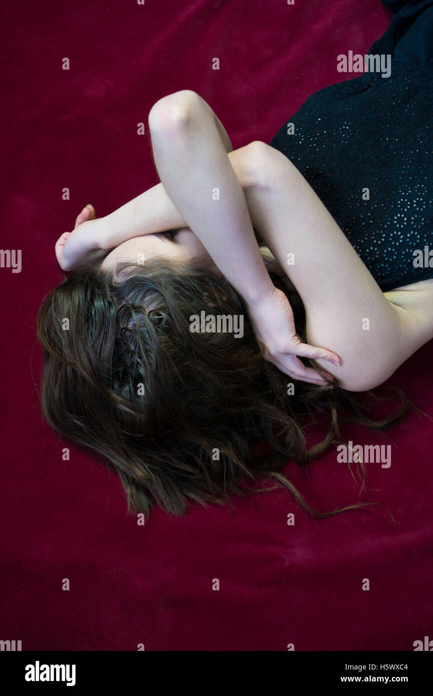 Young woman hiding face with hands laying down Stock Photo