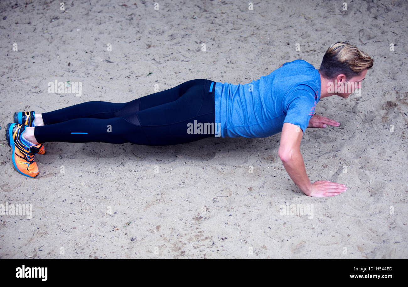 young man doing pushups outdoors in the sand Stock Photo