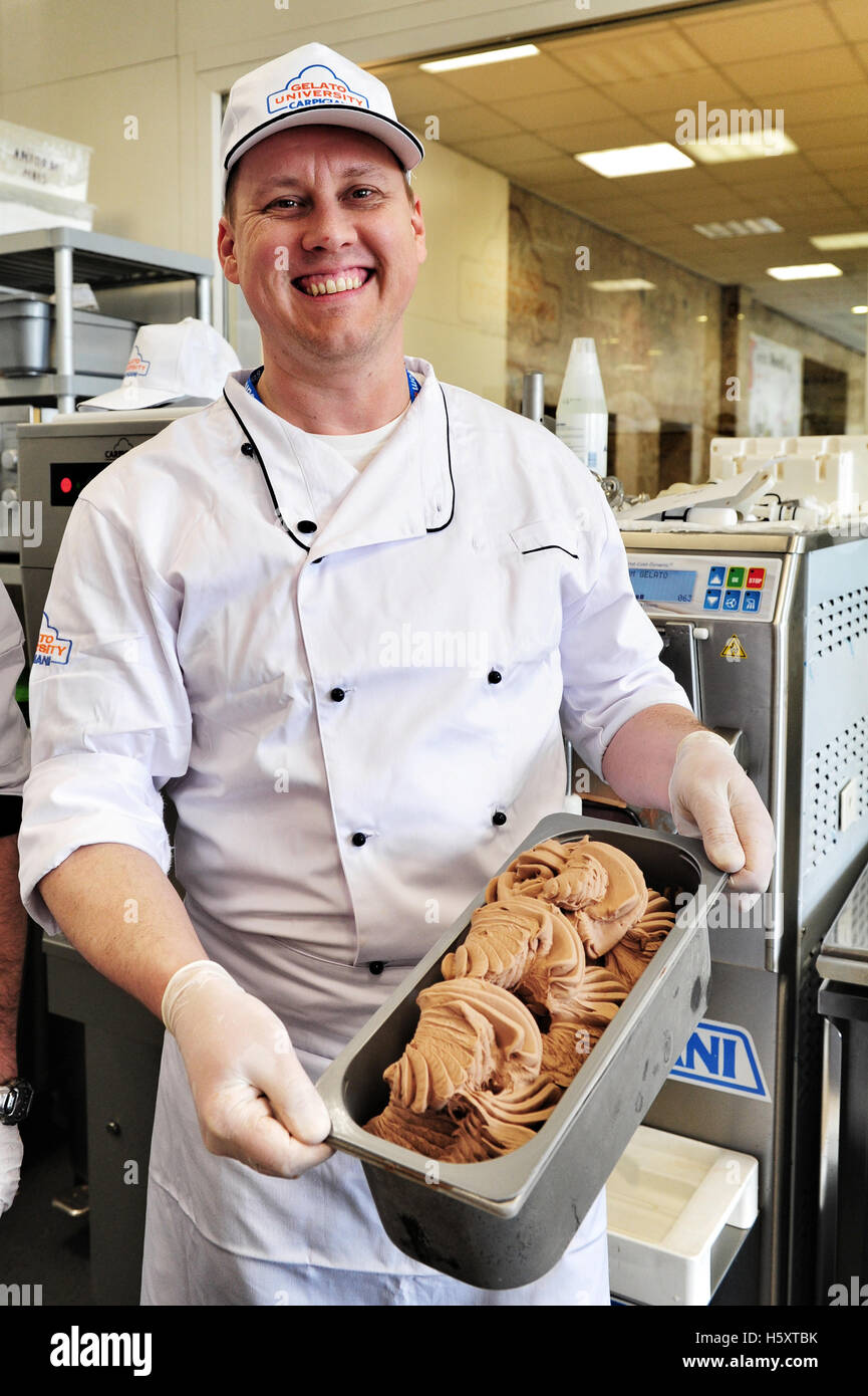 A student proudly shows the ice cream he has just made during a practical lesson at the Carpigiani Gelato University Stock Photo
