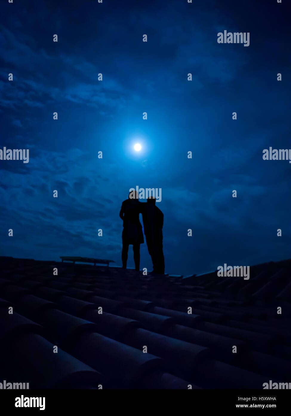 silhouette of couple on a roof under a full moon Stock Photo - Alamy