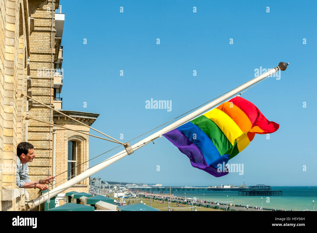 A Brighton and Hove Council worker hanging a gay pride flag from the council offices prior to the annual Pride march through the Stock Photo