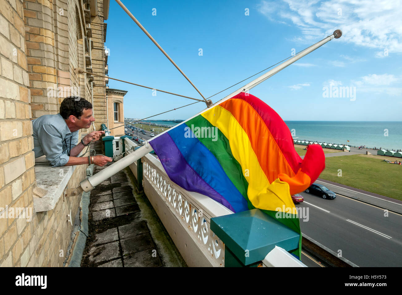 A Brighton and Hove Council worker hanging a gay pride flag from the council offices prior to the annual Pride march through the Stock Photo