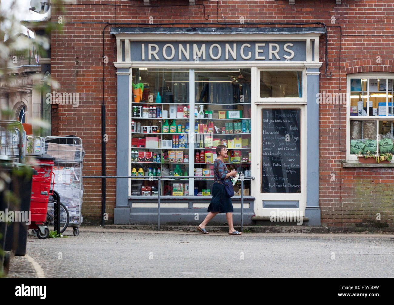 Woman walking past a traditional ironmongery shop Stock Photo