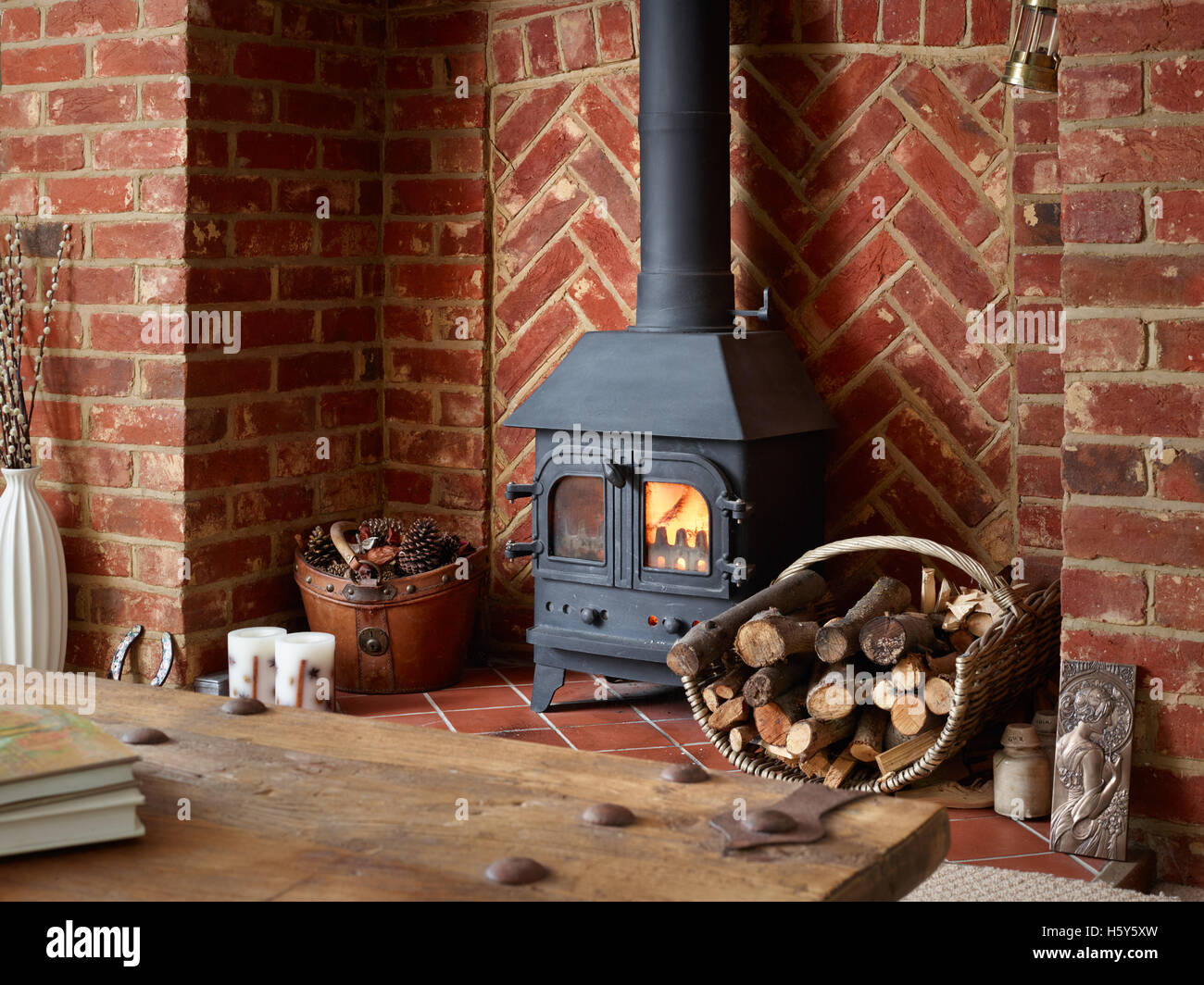 A homely, lifestyle view of a woodburner in a large brick fireplace in a country home Stock Photo