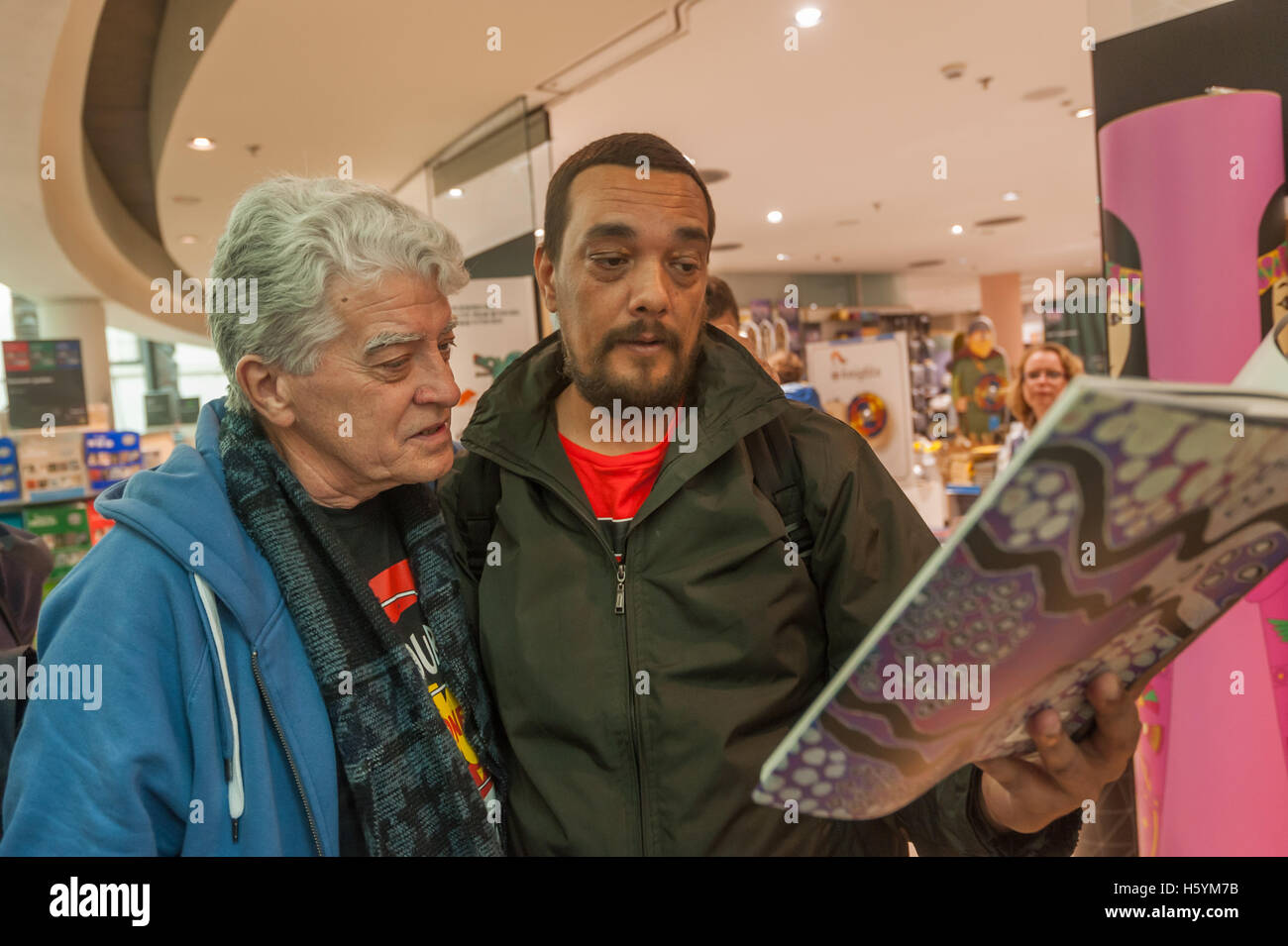 London, UK. 22 October 2016. Rodney Kelly, a sixth-generation descendant of the Gweagal warrior Cooman shot in the leg by Captain Cook and his crew at their first landing in Australia at Botany Bay in 1770 looks at the illustration of his ancestor's shield in aBritish Museum exhibition catalogue. Credit:  Peter Marshall/Alamy Live News Stock Photo