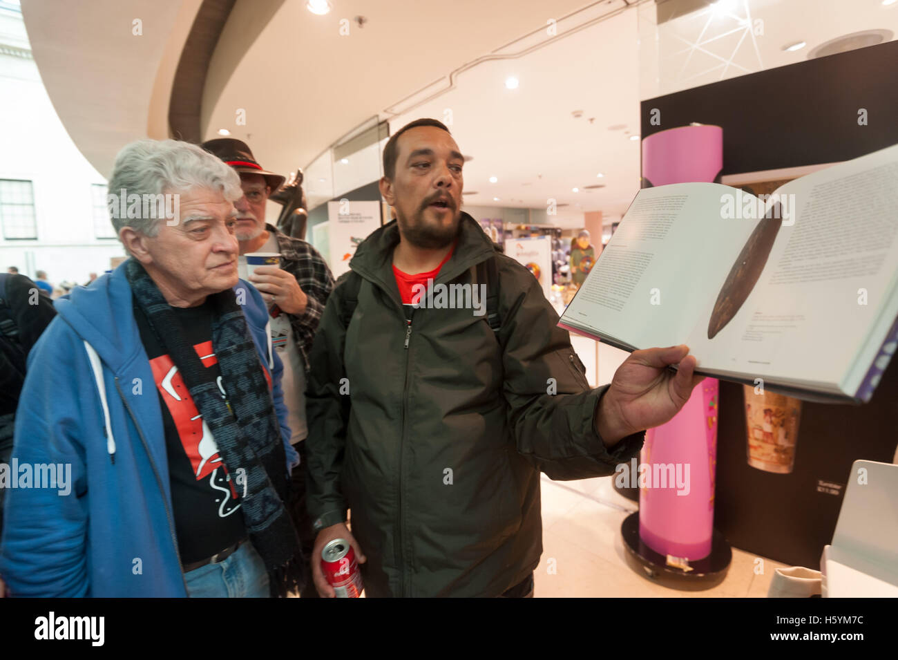 London, UK. 22 October 2016. Rodney Kelly, a sixth-generation descendant of the Gweagal warrior Cooman shot in the leg by Captain Cook and his crew at their first landing in Australia at Botany Bay in 1770 looks at the illustration of his ancestor's shield in aBritish Museum exhibition catalogue. Credit:  Peter Marshall/Alamy Live News Stock Photo