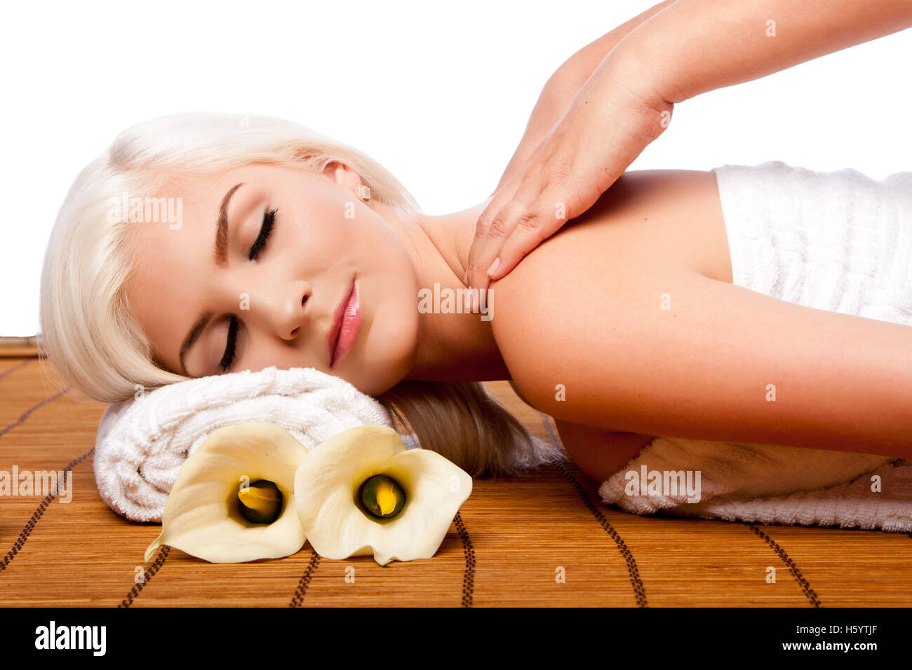 Beautiful young woman relaxing at spa getting therapeutic pampering shoulder massage. Stock Photo