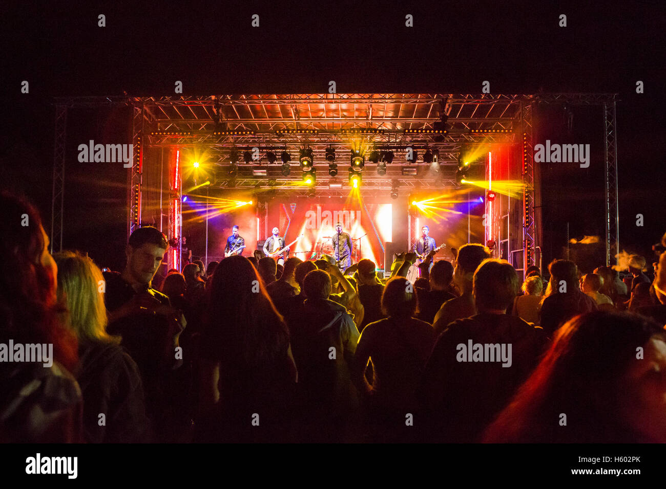 Crowds watch an Oasis tribute band play an atmospheric night time concert with colourful stage lighting at the local 2016 Phoenix festival in Cirencester, Uk. Stock Photo